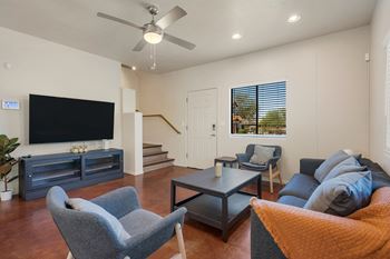 A living room with a television, a couch, a chair, and a coffee table.